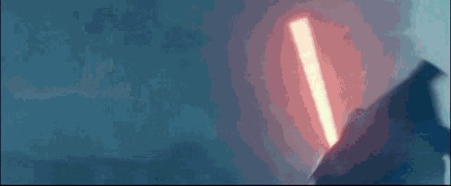 a person is holding a red lightsaber in their hand in the dark .