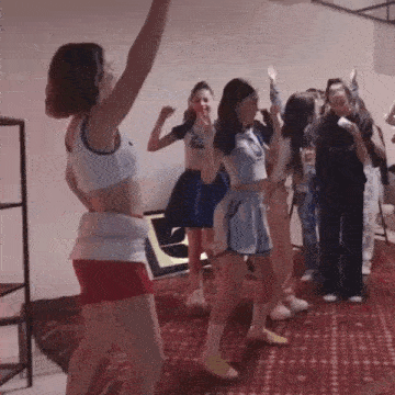 a group of women are dancing in a room with their arms in the air .