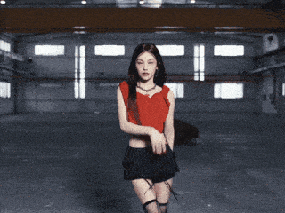 a woman in a red top and black skirt is dancing in a dark room