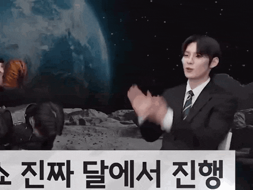 a man in a suit and tie is clapping his hands in front of a sign that says ' korean ' on it