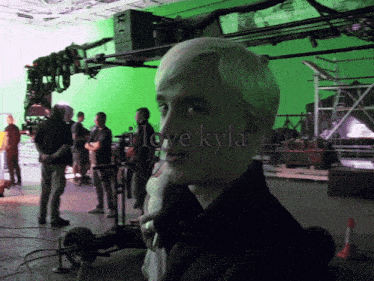 a man stands in front of a green screen with the words " i love kyla " above him