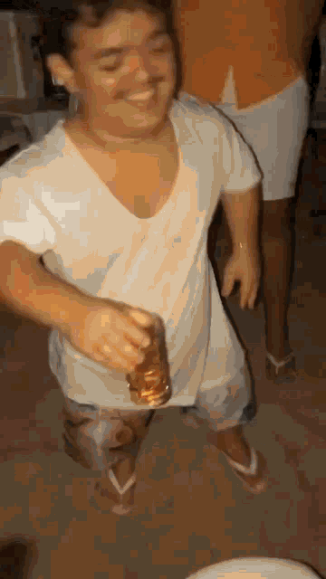 a man in a white shirt is holding a glass of beer and dancing .