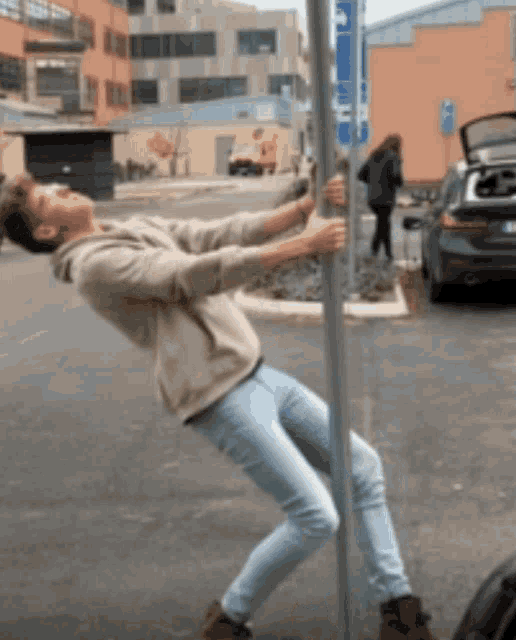 a man is climbing a pole in a parking lot with a car parked in the background