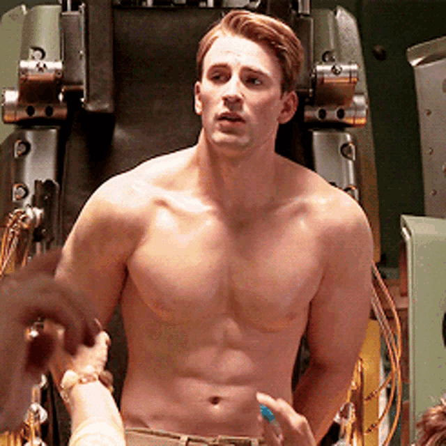 a shirtless man stands in front of a conveyor belt