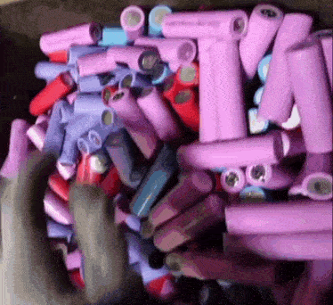 a bunch of purple and red batteries are stacked together