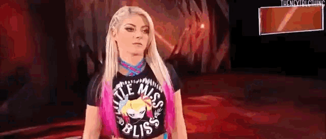 a woman in a little miss bliss t-shirt is standing in a ring .
