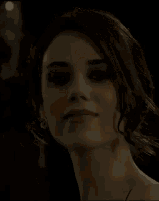 a close up of a woman 's face with dark hair and earrings