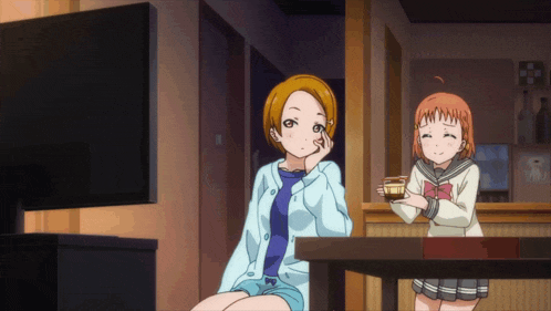 two anime girls sitting in front of a tv