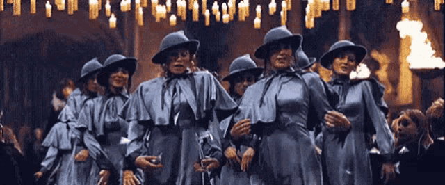 a group of people wearing hats and cloaks are standing in a room .