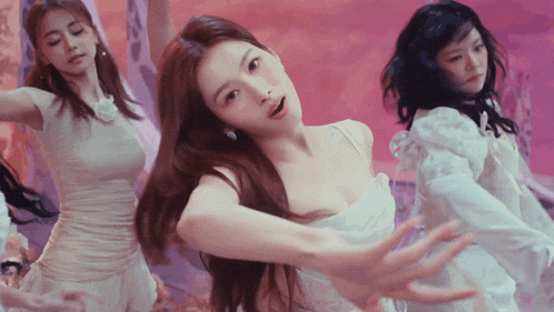 a woman in a white dress is dancing with two other women in white dresses .