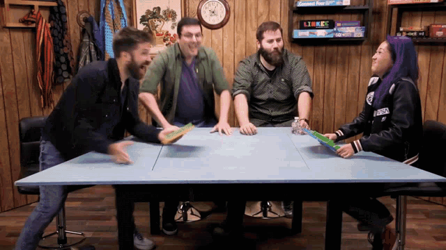 a group of people sitting around a table with a clock on the wall behind them that says 10:08
