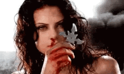 a woman with blood on her face is holding a sword .
