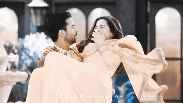 a man is carrying a woman in his arms and the words rishtacupid are on the bottom of the image