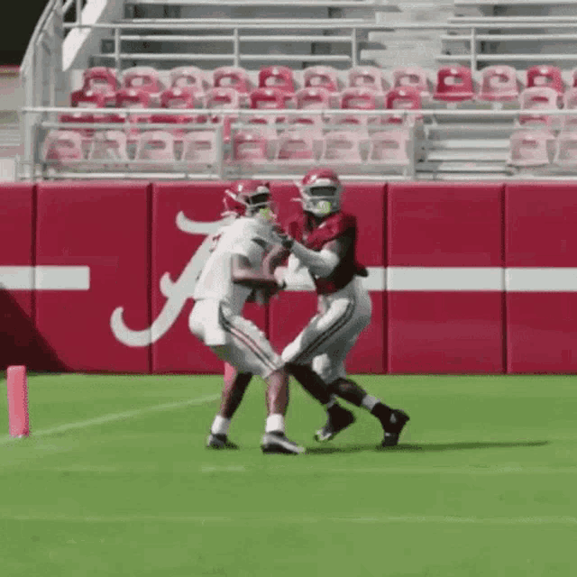 two football players on a field with the letter a on the wall