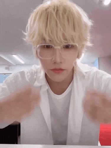 a man with blonde hair and glasses looks at the camera