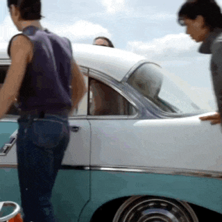 a man in a purple vest stands next to a white car