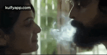 a man and a woman are kissing and smoking a cigarette .