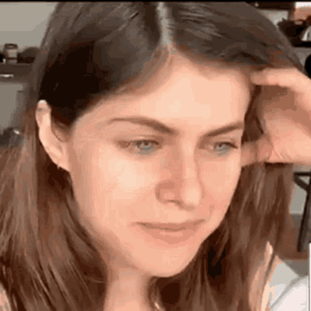 a close up of a woman 's face with her hand on her hair .