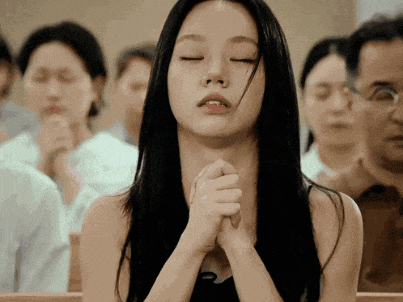 a woman is praying with her eyes closed in a church