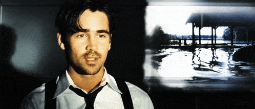 a man in a white shirt and black tie stands in front of a picture of a lake