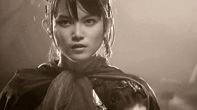 a black and white photo of a woman wearing a black cape