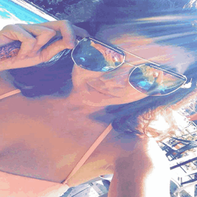 a woman wearing sunglasses takes a picture of herself