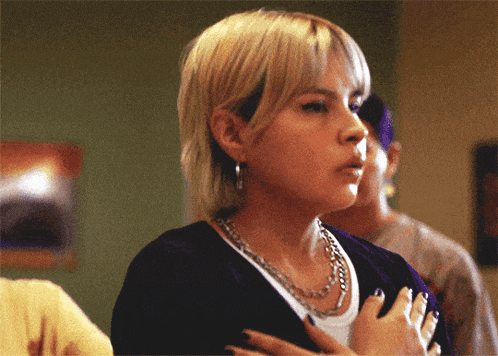 a woman with blonde hair is wearing a purple shirt and a silver chain around her neck
