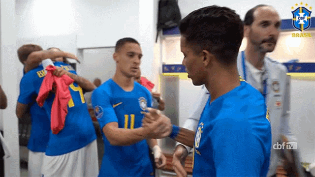 a group of soccer players in a locker room with the word brasil on the bottom right