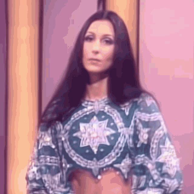 a woman with long hair is wearing a green crop top and a purple background .