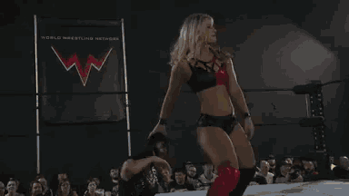 two women are wrestling in a ring and one of them is touching the other 's back .