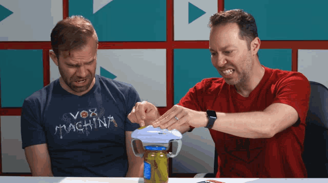 a man wearing a shirt that says vox machina sits next to a man wearing a red shirt