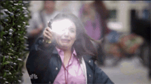 a woman in a pink shirt and a blue jacket is holding a flashlight
