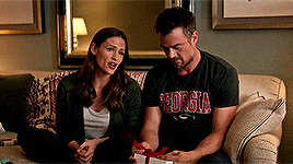 a man and a woman are sitting on a couch and the man is wearing a georgia shirt