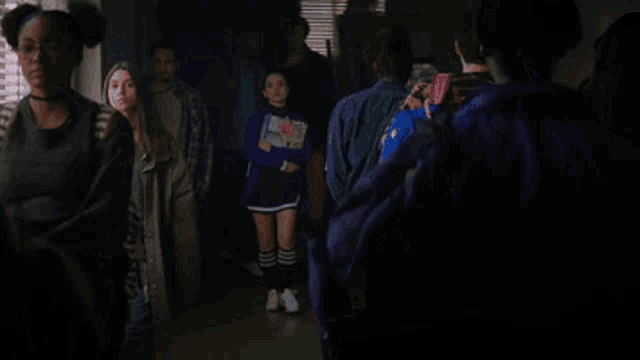 a group of people are standing in a hallway with a girl standing in the middle .