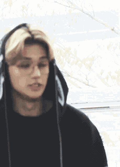 a close up of a person wearing a black hoodie and glasses
