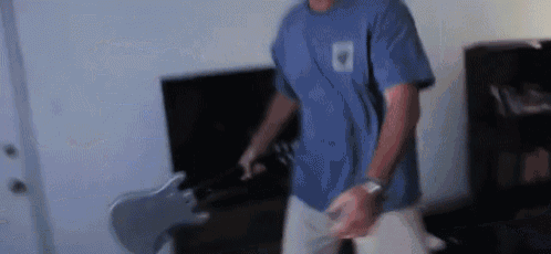 a man in a blue shirt is playing a guitar in a living room