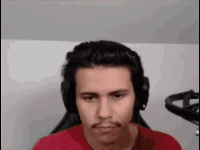 the man is wearing headphones and a red shirt .