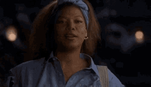 a woman wearing a blue shirt and a headband is laughing in the dark .