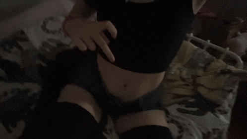 a woman in a black crop top and shorts is laying on a bed