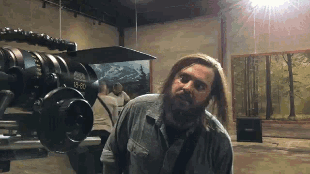 a man with a beard is standing in front of a camera that says 16-80