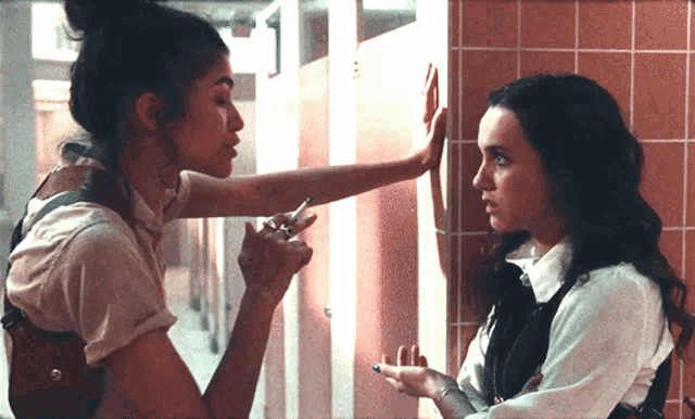 two women standing next to each other in a bathroom stall