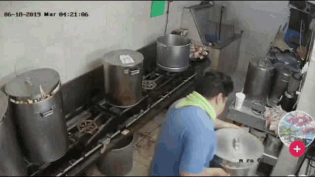 a man in a blue shirt is cooking in a kitchen with pots and pans on the stove