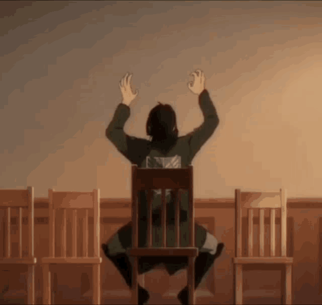 a man is sitting in a chair with his hands in the air