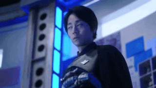 a man is standing in a room with his eyes closed and a blue light behind him .