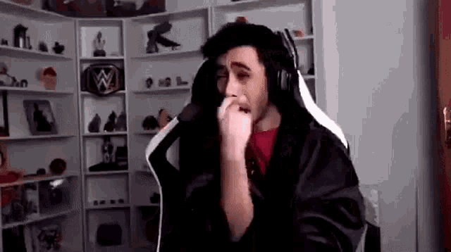 a man wearing headphones is sitting in a chair in front of a shelf .