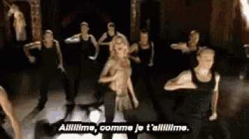 a group of people are dancing in a dark room and a woman is standing in the middle .
