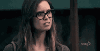 a woman wearing glasses is making a funny face and the word credo is behind her .