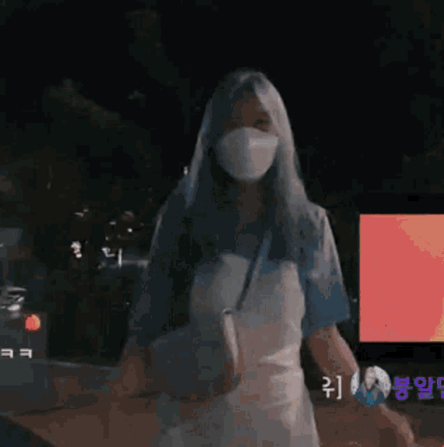 a woman wearing a mask stands in front of a sign that says momo on it