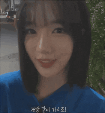 a girl wearing a blue shirt is smiling with a foreign language written on her face