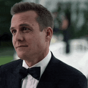 a man in a tuxedo and bow tie looks to the side